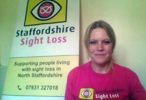 Image shows photo of our Service Manager Suzanne streaming a FB live video, she is wearing a pink SSLA t-shirt and sitting in front of a SSLA roller-banner that has our logo and contact details on it