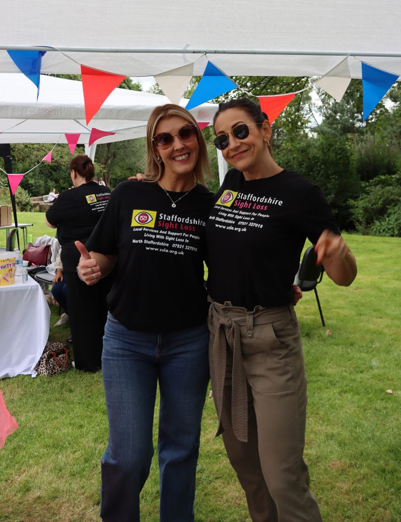 This image shows 2 volunteers from the hanley economic Building society in their staffs sight loss tshirts, they are both smiling and wearing sun glasses.